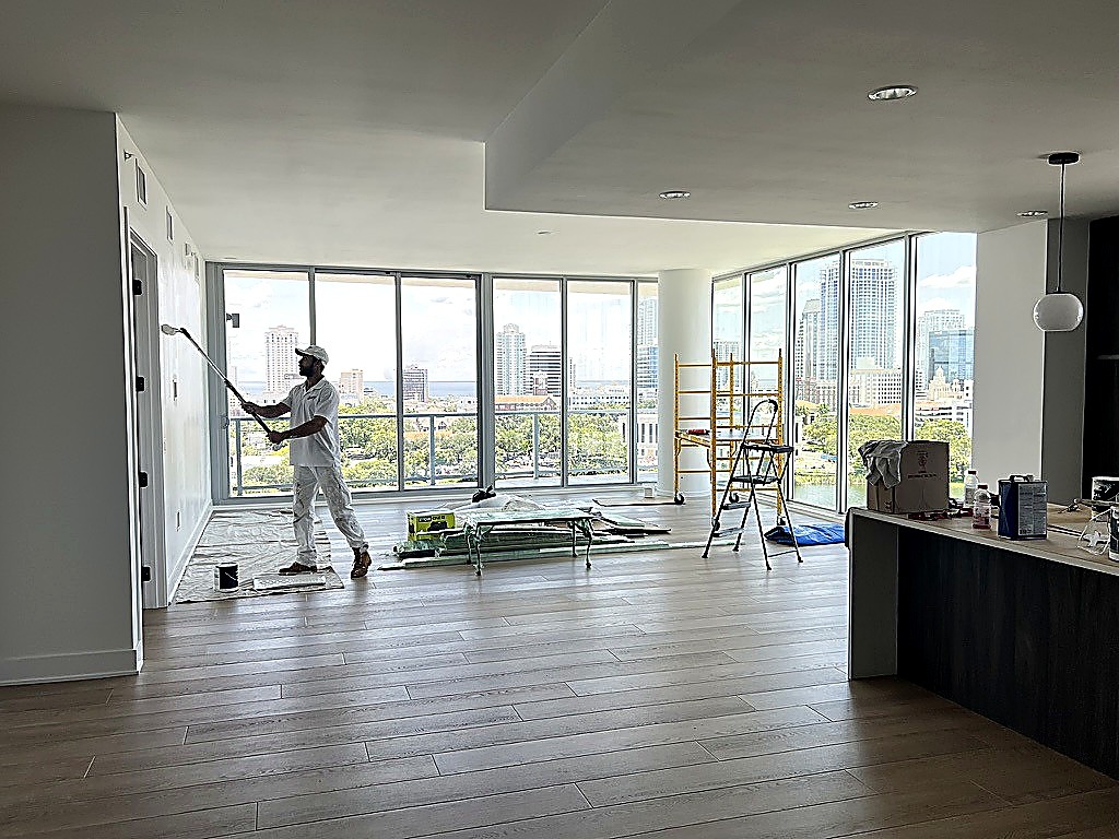 Noah Kanwal painting a luxury high-rise interior with a roller